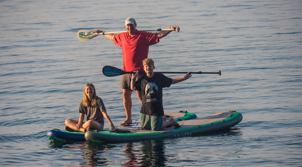 man with grandkids on paddle board